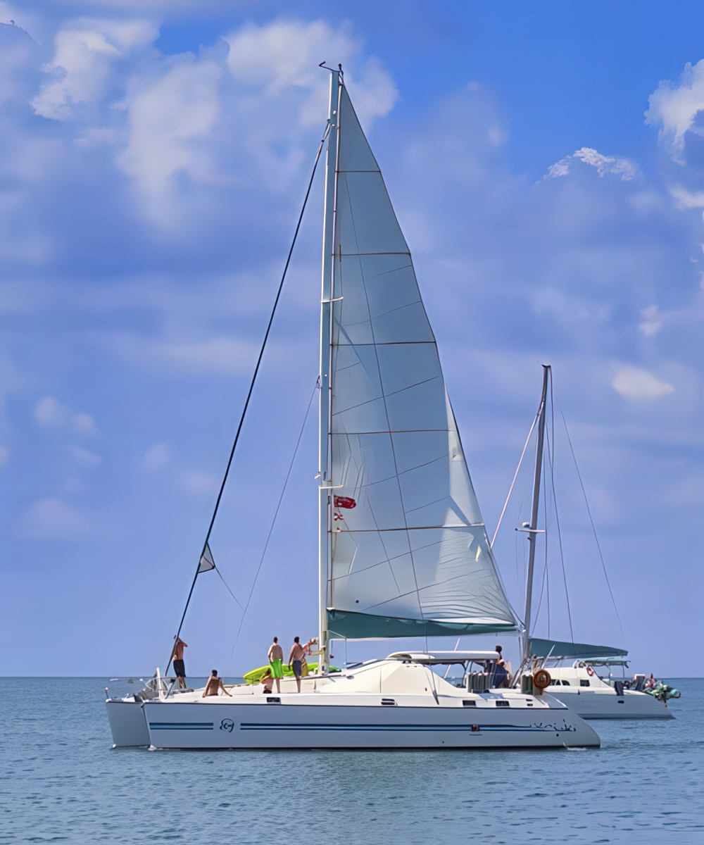 Sailing Placencia - Authentic Travel Belize Catamaran sailing off the coast of Placencia, a scenic highlight of a Belize adventure travel experience.