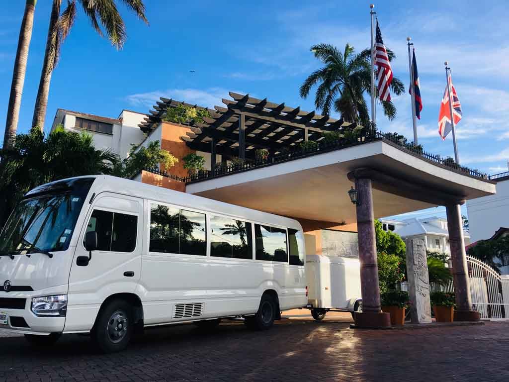 ToyotaCoaster - Authentic Travel Belize White Toyota Coaster with 29 passengers ready for travel, parked at the entrance of a boutique property in San Ignacio—part of premium Belize transportation services.