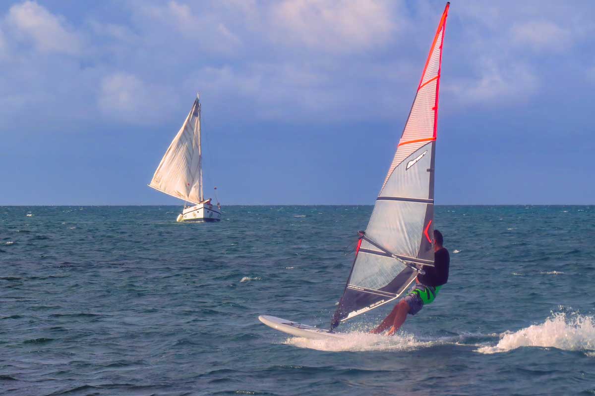 Windsurfer enjoying turquoise Caribbean waters in front of San Pedro, showcasing the active lifestyle offered by the best all-inclusive resorts in Ambergris Caye.