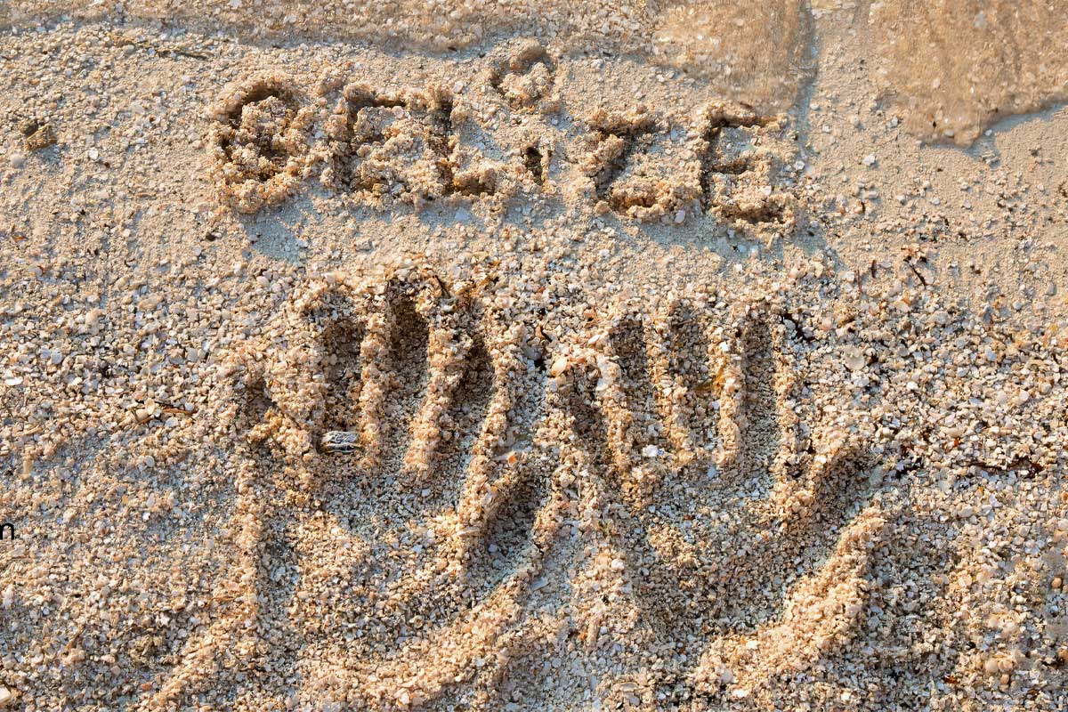 Belize Handprints of a man and woman in the white sand on a tropical beach in Belize, symbolizing romance and connection — perfect for Belize vacation packages for couples.
