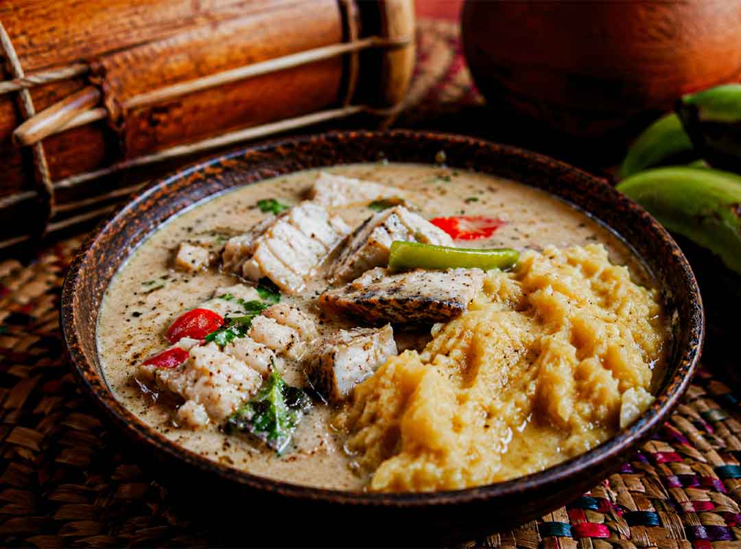Hudut-Belize-typical-dish - Authentic Travel Belize Traditional Garifuna hudut dish with coconut fish stew and mashed plantain served in a rustic bowl during a cultural Garifuna Drumming Workshop, Belize, surrounded by tropical textures and authentic Caribbean