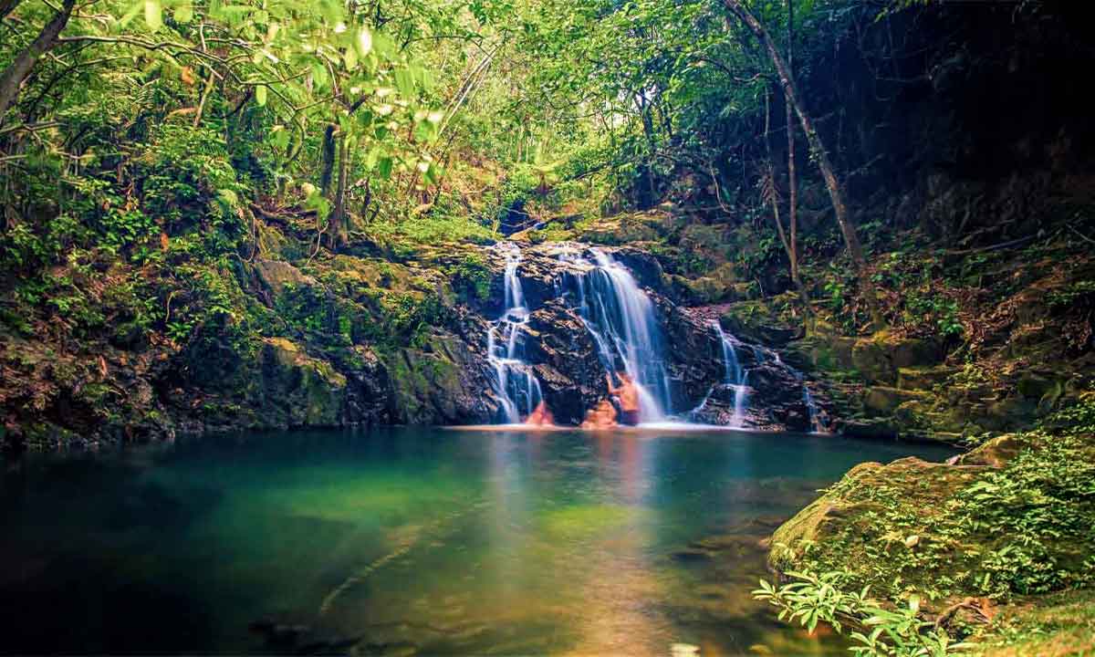 Soft-Adventure-Family-Journey - Authentic Travel Belize Belize Family Vacations with parents and children enjoying a refreshing swim beneath a waterfall in the tropical forest of Belize.